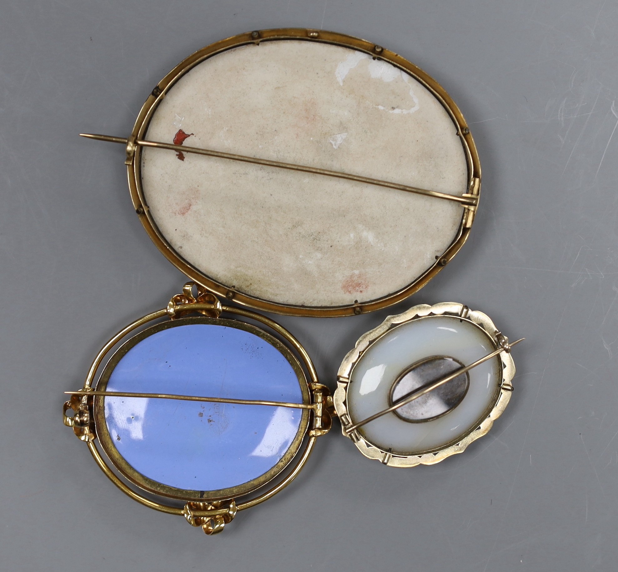 A Victorian 15ct gold mounted porcelain plaque, decorated with the Madonna della Sedia, 8cm, a Swiss landscape enamel brooch with 15ct mount, 6.5cm and a Pinchbeck brooch with turquoise set foliate decoration